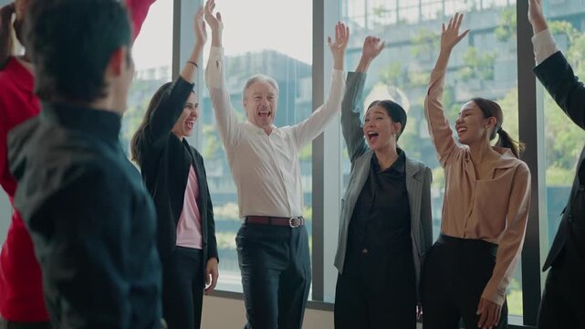 Joyful Business Team Celebrating Victory: A dynamic business team celebrates a significant win, arms raised in elation and triumph, against a backdrop of a modern office interior.