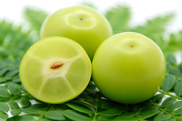 Obraz premium Three green amla fruits one cut showing seed on green leaves leaf