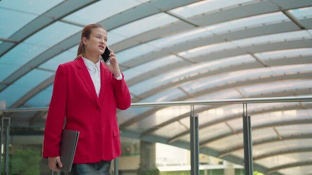Power Commuting: A poised figure strides confidently, engaged in an important call, a blend of city energy and professional focus, making their way through an architectural walkway.