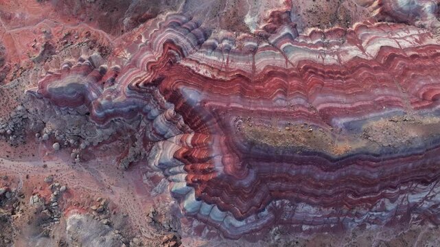 Aerial view of colorful striped bentonite hills with red and purple layers in the desert of Hanksville, Utah, United States.