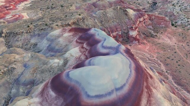 Aerial view of the colorful Bentonite Hills with vibrant red and purple stripes across the desert landscape in Hanksville, Utah, United States.