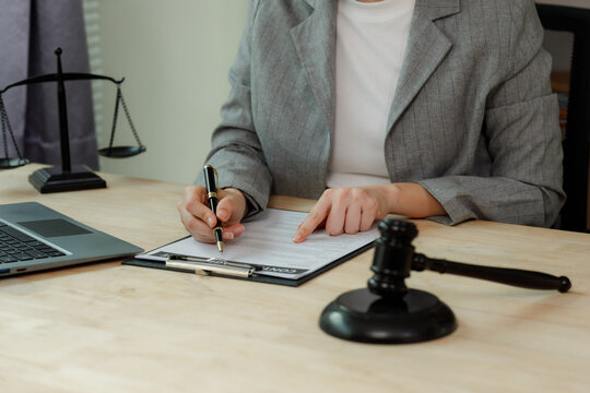 Close-up of a lawyer's hand reviewing and vetting a complex employment contract with a pen, ensuring all clauses are legally sound and accurate.