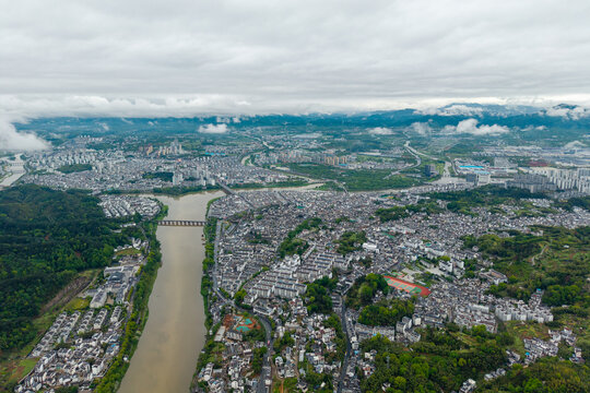 An aerial view shows the historical architecture of the Huizhou Ancient City located in She County of Anhui province in China surrounded by a winding river and green mountains under a cloudy sky