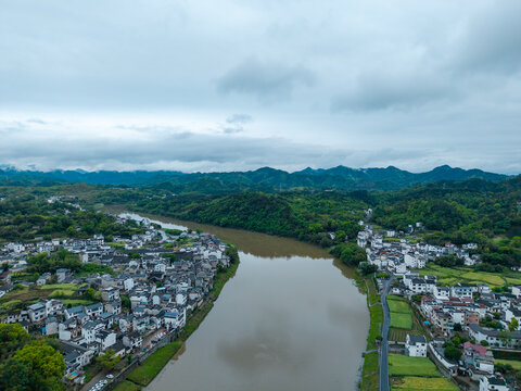 An aerial view shows the traditional houses of Huizhou Ancient City located in She County of Anhui Province in China with a wide river flowing through the lush green landscape