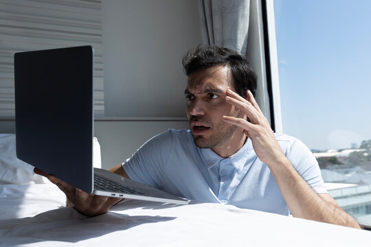 Worried man looking at the laptop screen expressing tension while analyzing unexpected data.