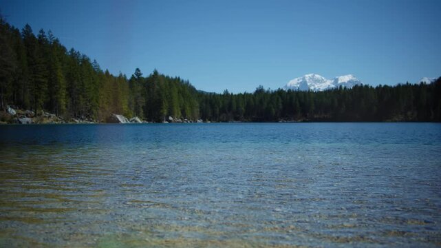 Snow-capped peak of the Hochkalter mountain reflecting in the water of Lake Hintersee, Berchtesgaden, Germany.