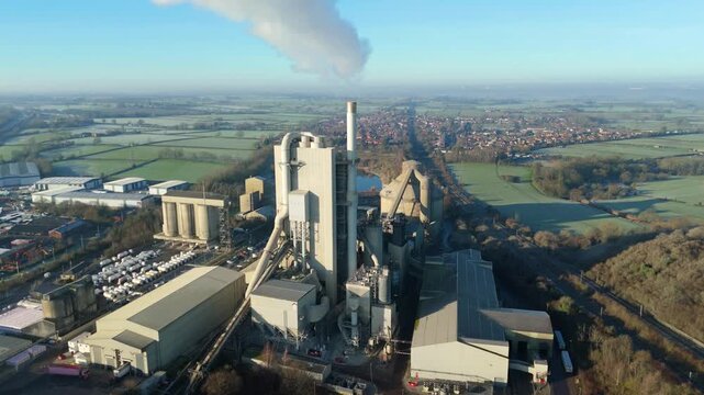 Top down aerial perspective of the industrial infrastructure and kiln systems at a cement factory.