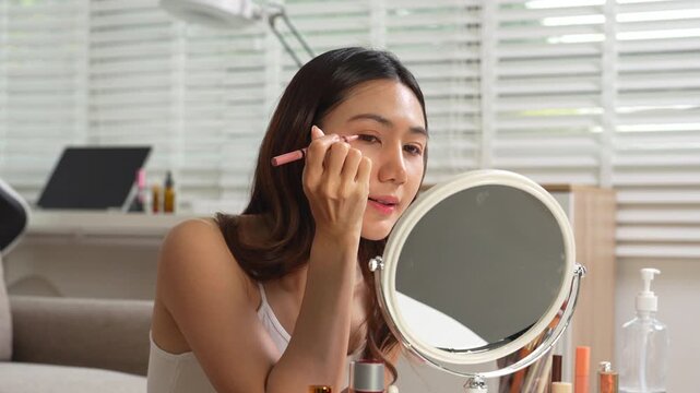 Asian beauty influencer recording makeup tutorial at home 