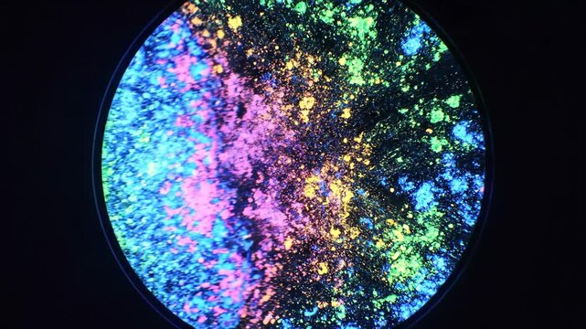 A vibrant circular design with multicolored splatters and sparks on a black background