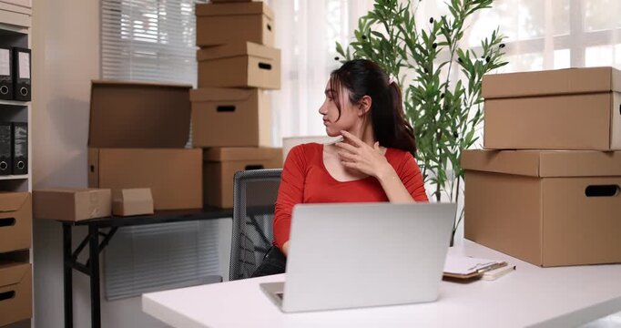 Asian entrepreneur joyfully fulfilling shipping orders from her home office with a laptop and barcode sme scanner
