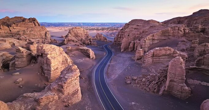 Scenic winding asphalt road passing through majestic desert rock formations and canyons in Xinjiang, China.