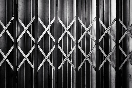 Monochrome close up of industrial metal folding security gate lattice.