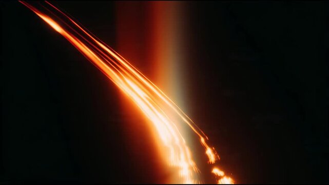 Close up of a fiery stream of molten metal being poured in a dark foundry.
