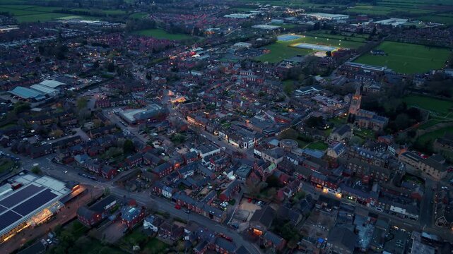 Aerial view of the historic market town of Oakham with its illuminated streets, church spire, and residential rooftops at dusk Oakham, England, United Kingdom.