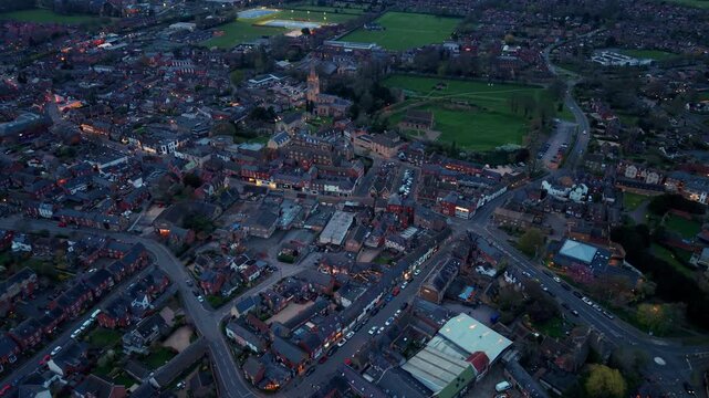 Aerial view of the historic town of Oakham with illuminated streets and buildings at twilight surrounded by green fields in Oakham, England, United Kingdom.