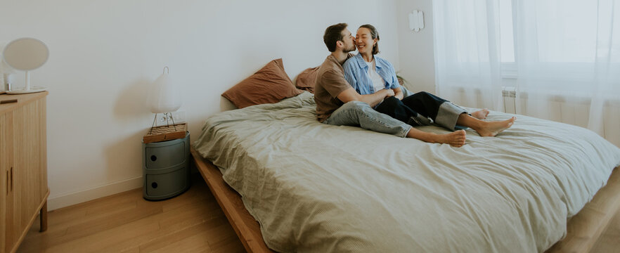 A Korean woman and a Caucasian man share intimate moments in bed