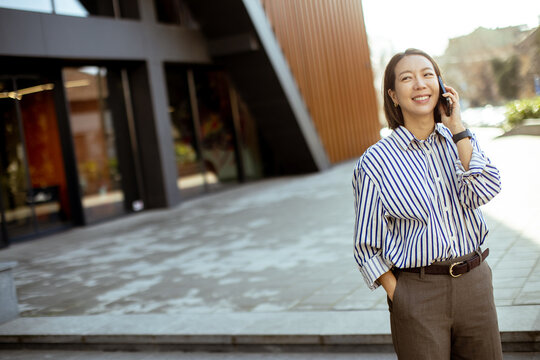 Korean woman talking on the phone outside a modern building during the day