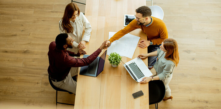 Team meeting in a bright office, featuring handshakes and collaboration