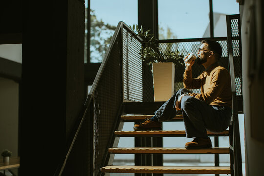 Enjoying a warm drink while sitting on the stairs during a sunny afternoon