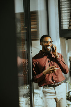 Smiling man in a stylish shirt enjoys a lively phone conversation indoors