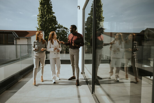 Three professionals engage in dynamic conversation on a modern balcony together