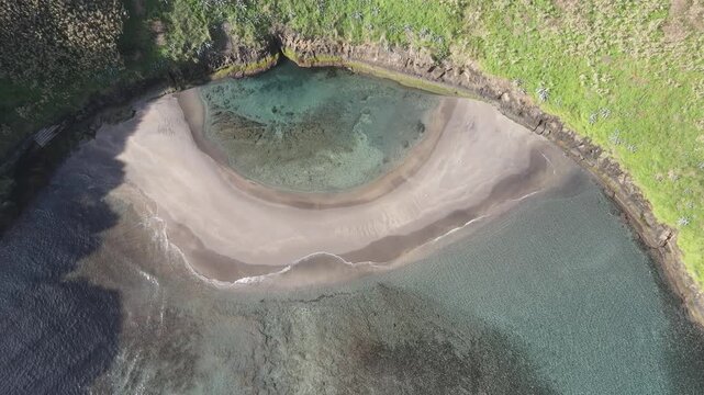 Slow aerial top-down rotation over the turquoise lagoon inside the volcanic crater of Vila Franca do Campo islet.