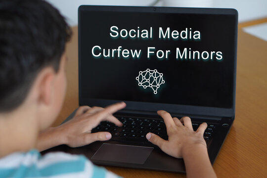 social media curfew for minors. Digital safety and well-being in childhood and adolescence. Child typing on his laptop