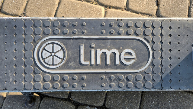 A top-down view shows the textured rubber deck of a Lime electric scooter, featuring the circular citrus logo and brand name on a grey grip. Image taken on April 24, 2026 in Bucharest, Romania.