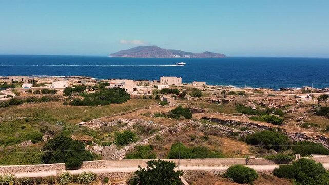 Rising drone shot over Favignana island, Egadi Islands, Sicily. Ancient stone ruins below, deep blue Mediterranean sea and Levanzo island gradually revealed on the horizon.