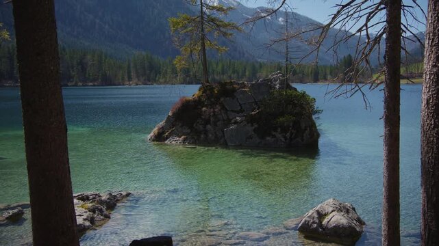 Small trees growing on a rock island in the middle of scenic Hintersee mountain lake, Berchtesgaden.