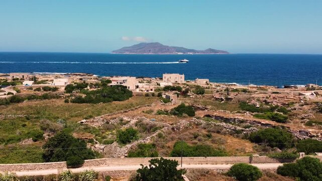 Reverse drone shot pulling back over Favignana island, Egadi Islands, Sicily. Ancient stone ruins and coastline revealed as the frame widens, with Levanzo island across the deep blue Mediterranean.