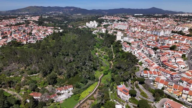 Aerial view of residential neighborhoods with red-roofed houses divided by a lush green valley Cascais, Lisbon, Portugal.