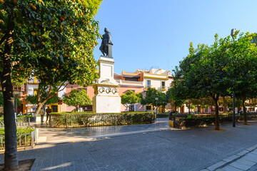 Obraz premium The shaded urban Plaza del Museo a Seville across from the Museum of Fine Arts in Seville, Spain with the monument to Bartolome Esteban Murillo the sculptor.