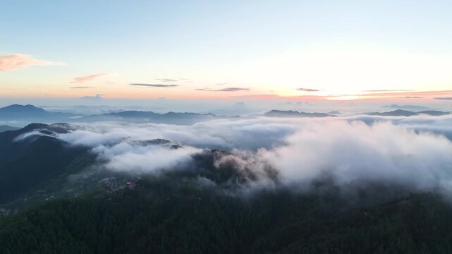 Breathtaking aerial drone footage flying high above a dense sea of clouds during a golden sunrise in the Himalayas near Shimla, India.