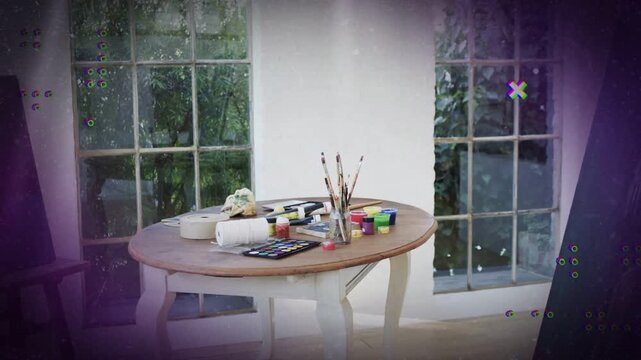 Round wooden craft table sitting by paned window looping animated overlays revealing paint supplies