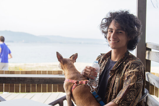 Teenager enjoying time with his dog at the beach bar