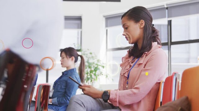 Woman in pink blouse using tablet in training, reacting to speaker, animated shapes overlaying them