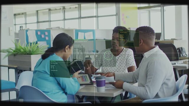 Left woman tapping tablet, HUD overlay aligning over faces, team collaborating on business plan