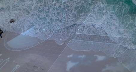 Fototapeta premium Breaking shore showing foamy surf washing onto coastal beach, with overlay and dark rock upper-left