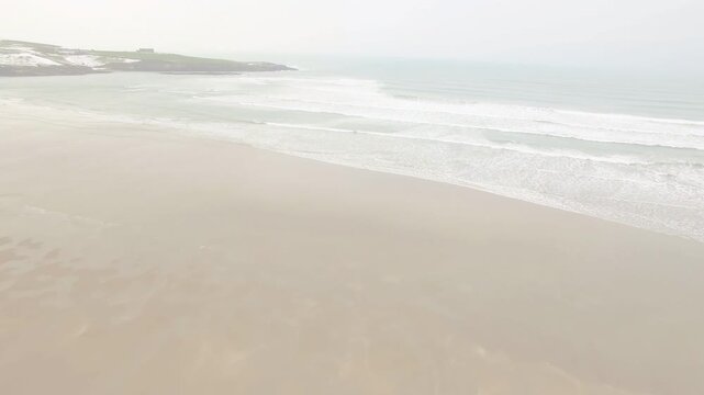 Drone descending and panning, revealing sandy beach, breaking waves and fading dashed overlay