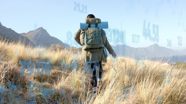 Camera tracking hiker growing data overlay around her, walking uphill steadying pack for travel nav