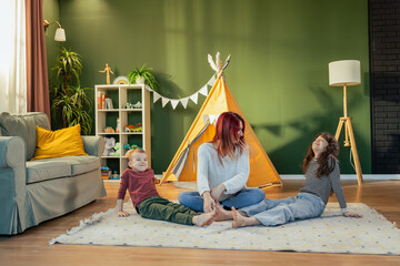 Mother playing with children in living room with teepee tent © MexChriss