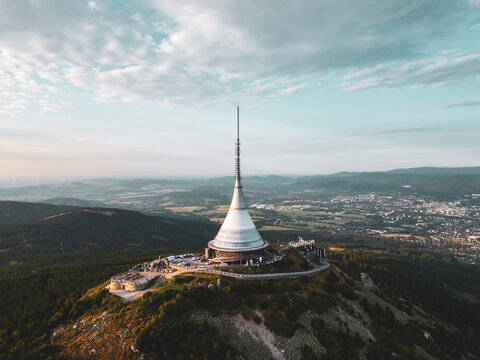 Jested Mountain Hotel, nestled in Liberec, showcases modern architecture against a picturesque sunset. The scene captures the hotel's unique silhouette with surrounding landscapes.