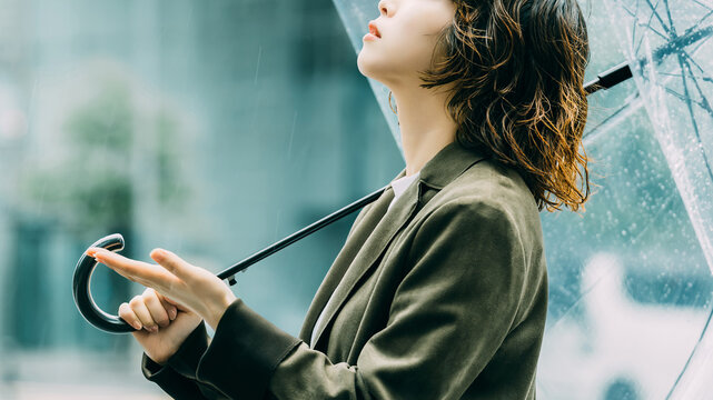 雨の日に傘をさす日本人女性・ビジネスウーマンのイメージ（LP・バナー向け）, Japanese Businesswoman with Umbrella on Rainy Day