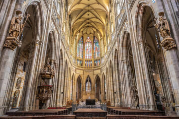 Obraz premium Visitors explore the interior of St. Vitus Cathedral at Prague Castle in Czech Republic. The tall arches and stained glass windows create a unique atmosphere for all.