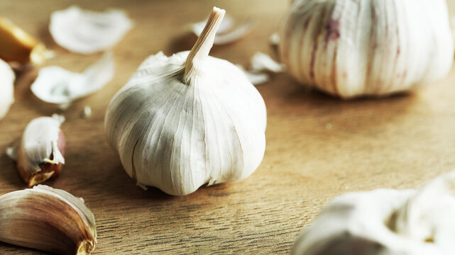 Fresh garlic bulbs on wooden table illuminated by soft window light with natural shadows and warm rustic atmosphere