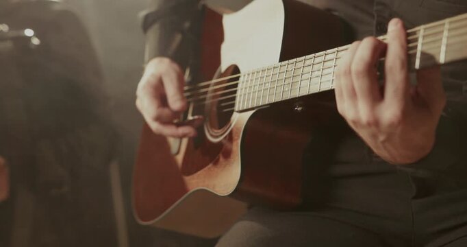 Close-up of musicians&rsquo; hands playing accordion and acoustic guitar in warm smoky light, creating an intimate live performance mood