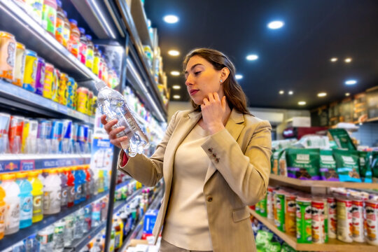 Woman choosing bottled water at convenience store in manhattan