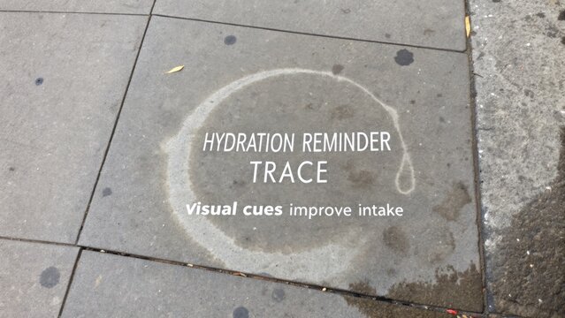 Urban Hydration Reminder on Sidewalk with Circular Water Stain and Informative Text Encouraging Fluid Intake for Healthy Living