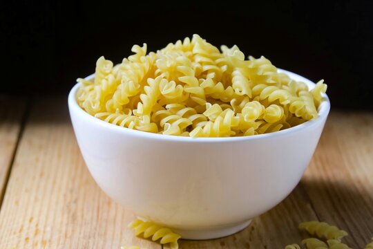 uncooked fusilli pasta in a bowl on wooden table